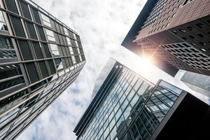 Looking up at the sky between tall corporate buildings.